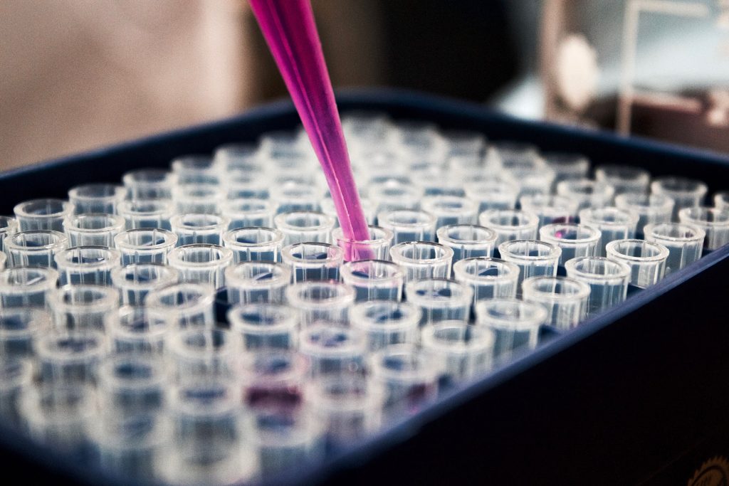 Pipette de liquide mauve dans un plateau d'éprouvettes